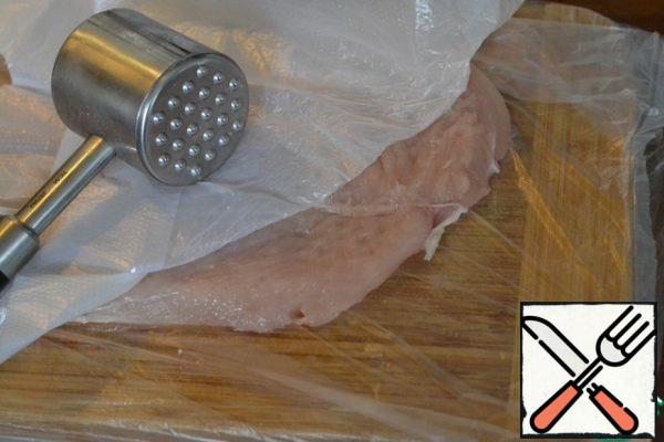 Cover the Board with pishevoy film, lay out the chicken breast, cover again with pishevoy film and carefully beat off. The main thing is not to break the breast. We need it whole.
