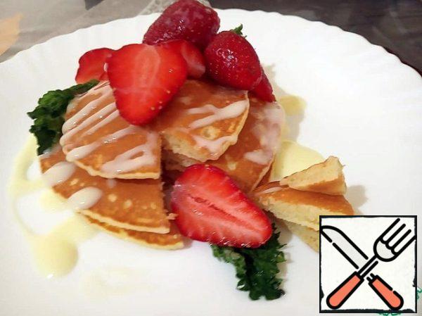 Ready-made pancake spread on a serving plate, pour condensed milk, decorate with strawberries and mint. Bon Appetit!