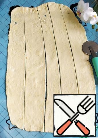Grease the silicone Mat with vegetable oil. Roll out the dough. Cut into strips 5-6 cm wide.