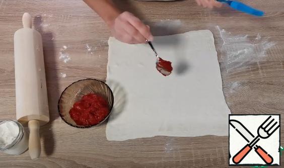 Roll out the dough and grease with tomato sauce.
