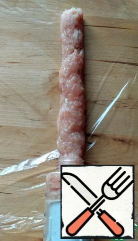 Cover the work surface with plastic wrap. Using a pastry syringe (without attachments), squeeze out the meat sausage. You can use a regular package by cutting off a corner.