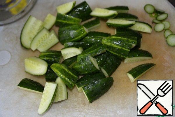 Cucumbers are washed, cut off the tips, cut into 4 parts along and then cut in half.