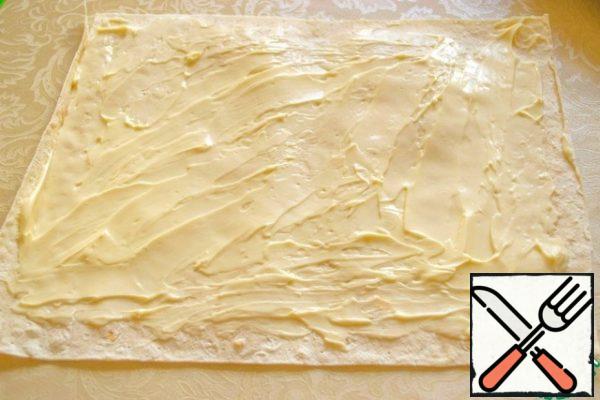 Cut the pita bread into small rectangles and smear with cheese.