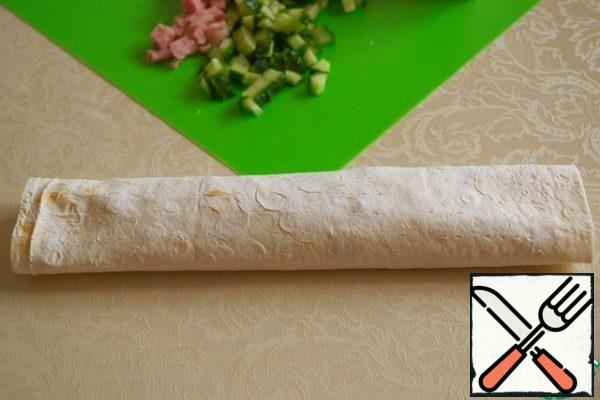 Roll into a roll, press down slightly so that the filling is evenly distributed throughout the pita bread.