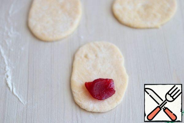 Divide the dough into equal pieces. Roll each piece into an oval shape. At the end of the oval tongue, put 1 teaspoon of cherry thermostable jam.