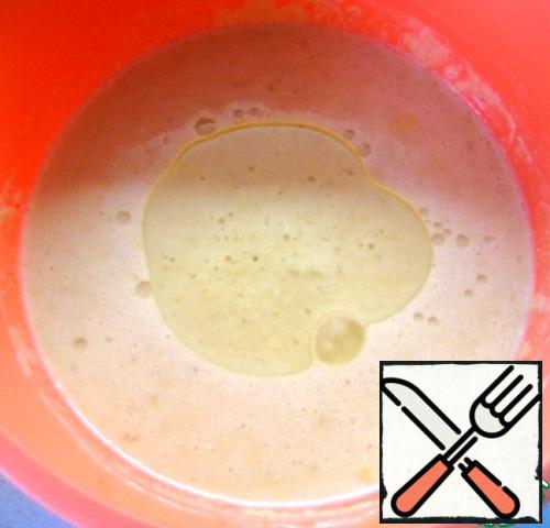 Add the baking soda to the flour mixture, pour in the egg-milk mixture, vegetable oil and mix the dough thoroughly. It turns out not thick, easily drains from the spoon.