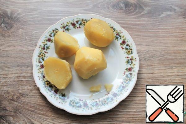 Peel the potatoes and boil in salt water until tender. Remove the potatoes to a plate and cool.