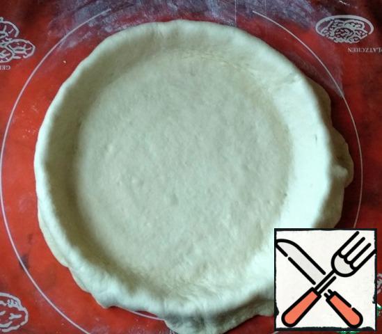 Then roll out the dough in a circle and cover it with a baking dish (diameter 28 cm) so that the edges of the dough hang over the sides. If necessary, cover the form with baking paper or foil, grease 1 tbsp of vegetable oil.