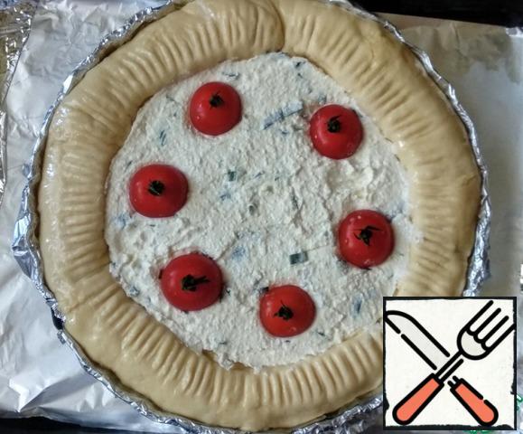 Spread the filling in the center of the pie. Wash the cherry tomatoes and spread them over the filling, drowning them in it.