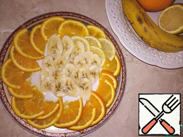 Closer to the end of 40 minutes of finding the future cake in the refrigerator, prepare washed and dried fruit: cut 1 medium-sized orange into thin semicircles, prepare 4 half-circles of lemon, 1 medium-sized banana cut into thin rings diagonally just before spreading, so as not to darken.