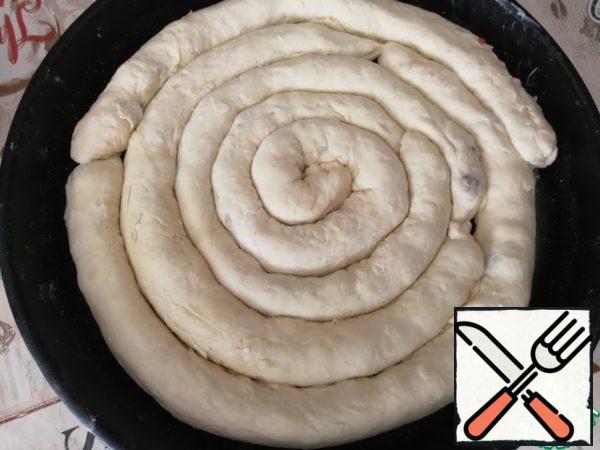 Pinch the edges, forming a roll. Grease a baking sheet with butter, lay out the rolls in the form of a snail.
