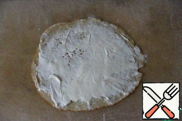 To prepare this snack, you need ready-made pancakes: not sweet or slightly sweet. It is convenient to take pancakes with a diameter of about 16 cm, comparable to the size of crab sticks.
Pancakes are evenly smeared with cottage cheese.