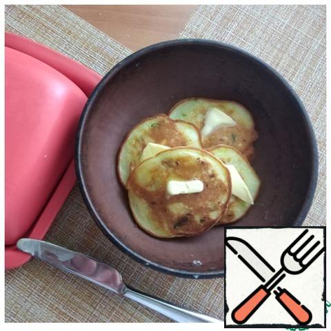 Removing the fritters from the pan, I put a small piece of butter on each one. I put it in an earthenware dish and cover it with a lid.