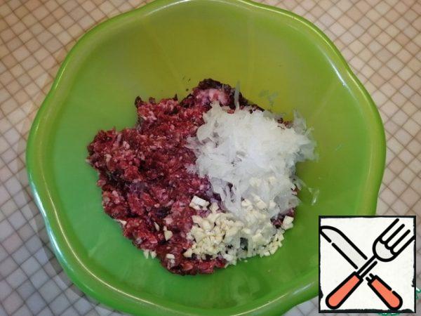 Add the onion grated on a large grater to the minced meat in a deep bowl. And finely chopped three cloves of garlic.