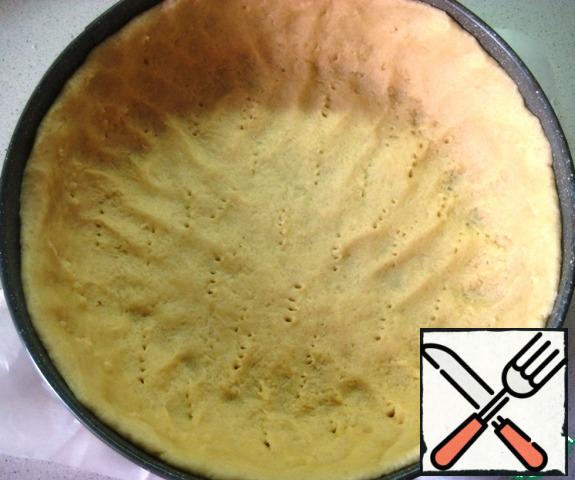 In a baking dish, put the dough and distribute, forming high sides (the diameter of the form is 24 cm, the bottom is covered with baking parchment). Prick with a fork.Send the dough to be baked in a preheated 180-degree oven for 10 minutes.