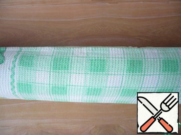 Now the biscuit is wrapped in a towel and left to cool in a rolled form.