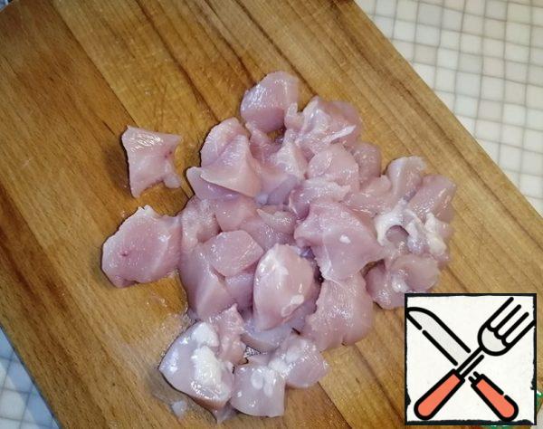 Cut the chicken fillet into small pieces. Transfer to a saucepan, cover with water and put on medium heat. Cook for 20 minutes.