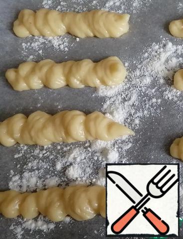 Spread the parchment on a baking sheet and sprinkle with flour. Squeeze out the dough strips for 6-7 cm. Send to bake in a preheated 200 degree oven for 25-30 minutes.