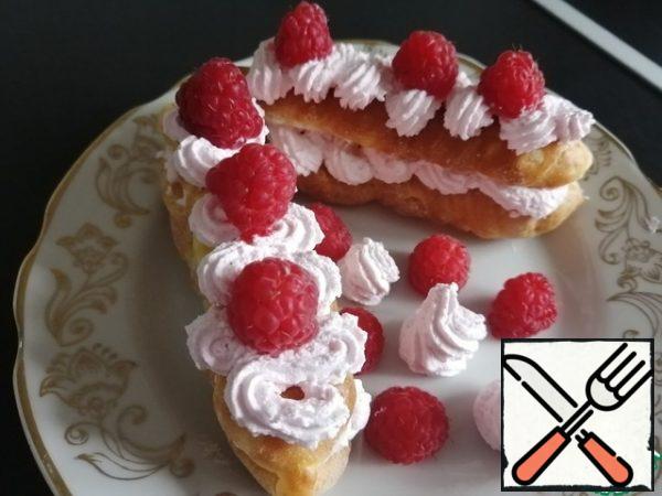 Cut the eclairs in half, apply the cream to the lower part, close the second half. Spread another layer of cream on top. Decorate with raspberries.