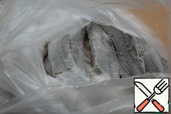 Put the capelin in a bag with flour and salt, tie the bag and shake it so that the flour and salt are evenly distributed on the fish.