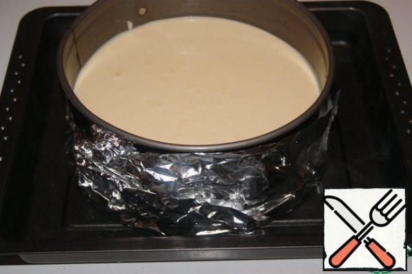 Very tightly wrap the bottom of the form with foil and place it in a baking tray with sides, which pour boiling water. Water should cover the bottom of the form by just 1.5 cm. This baking technology protects the bottom of the biscuit and cheese layer from burning, and the cheesecake itself is very tender.
Bake in a preheated 150"C oven for about 1 hour. Focus on your oven!