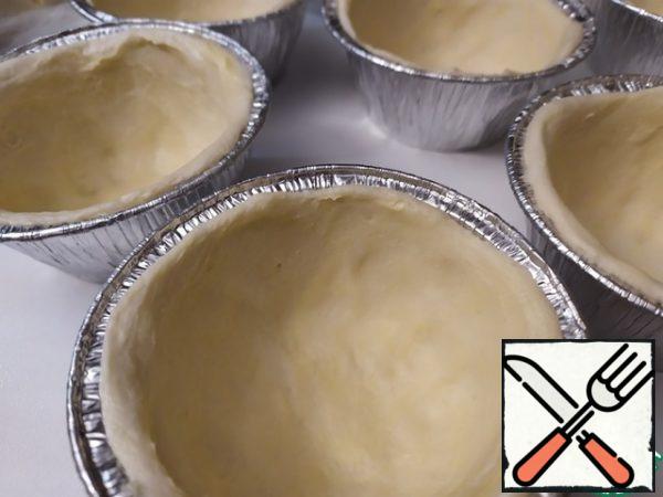 Moisten your fingers and distribute the dough in a thin layer on the walls and bottom.