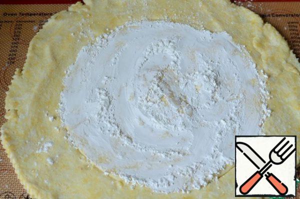 Roll out the dough in a circle. Mix the starch and 1.5 tbsp powdered sugar.
Stepping back from the edges, the dough is powdered with a mixture of starch (2/3).