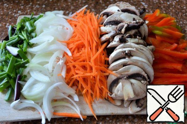 Cut into thin strips of pepper, mushrooms, onion feathers, carrots straws. The dish is prepared quickly, so the slicing should be ready.