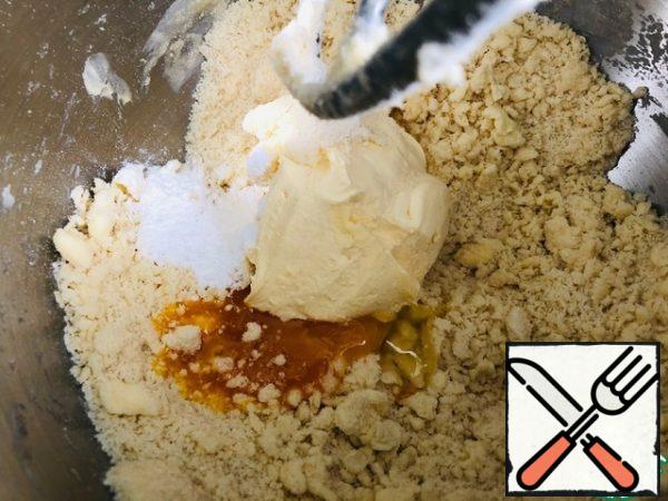 - Add to the crumbs the egg yolk, baking powder, sour cream, (egg yolk and sour cream should be cold). Stir at low speed of the mixer to combine the dough.