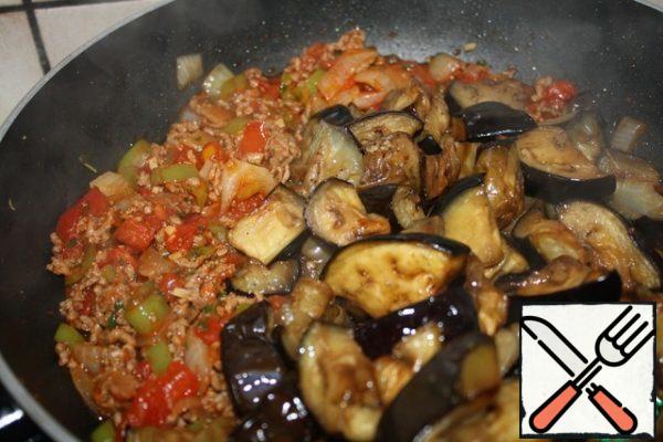 Then add the eggplant and bulgur. Add about 150 ml of water and salt to taste.
Simmer on low heat under a lid for about 15 minutes.