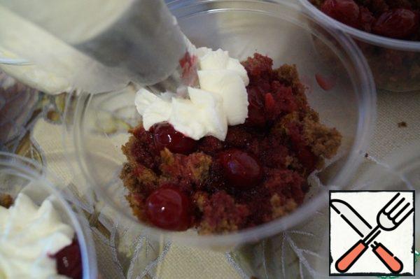 Meanwhile, prepare the cream. Beat the cooled cream with a mixer to light peaks. Then add the cooled cream cheese and powdered sugar, and beat again until smooth. Put the cream in a pastry bag with a nozzle and on top of the biscuit with cherries, on the entire surface, we will detach not large cream flowers.
