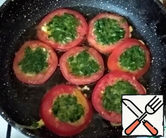 In a preheated frying pan, greased with olive oil (2 tbsp), put the tomato rings, pour the beaten eggs with herbs into them, fry on both sides.
