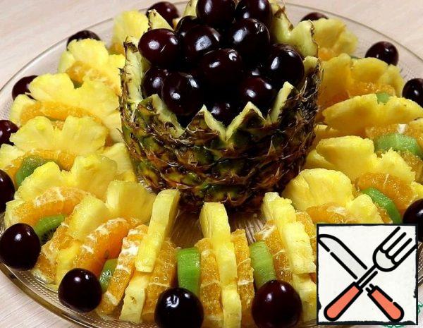 1. cut off the bottom and top of the pineapple. Cut out the pulp.
2. Put the cut off bottom part of the pineapple in place. The result is a basket with a bottom.
3. Cut the cloves along the edge of the basket with a knife. Fill with cherries (or any other berry)
4. peel Kiwi and orange, cut lengthwise into 2 parts, cut into half rings.
5. The pineapple split into two parts. Cut into half rings.
6. Place a basket of berries on the center of the dish. Spread the kiwi, pineapple and orange in a circle.
7. in a circle, decorate with berries.