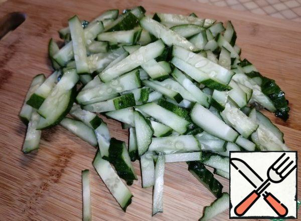 Cut the cucumbers into long strips. Pour out to the crab sticks.