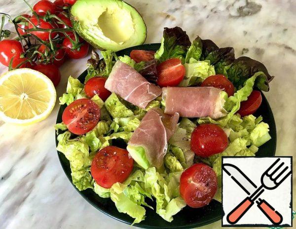 Peel and slice the avocado. Wrap each piece in a prosciutto slice. Put on a plate with fresh lettuce, cherry tomatoes and pour the dressing of lemon juice and olive oil. Add salt and pepper to taste.