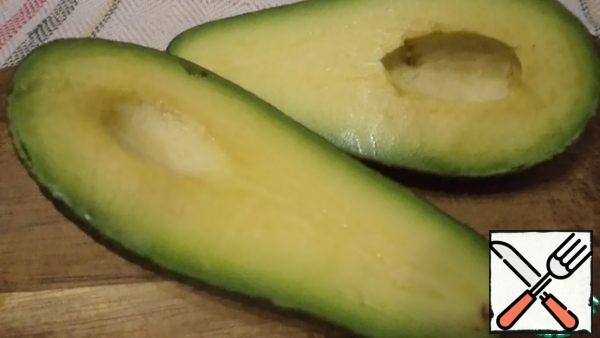 Cut the avocado into 2 parts and remove the stone.