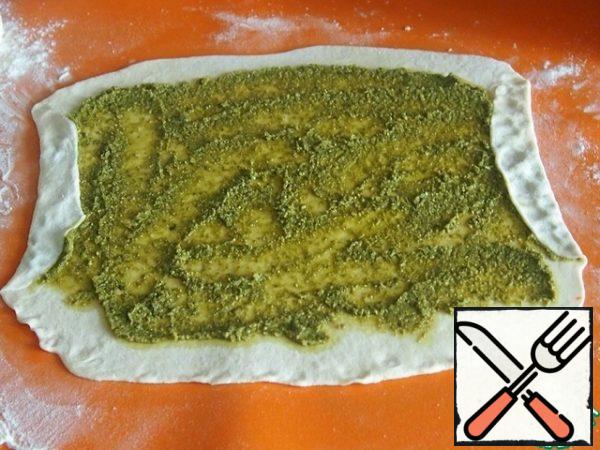 To get pesto, you need to crush the Basil leaves and all the other ingredients in a mixer into a paste. I do not have a photo, because when I did it, I did not know that I would need photos. You can also use ready-made store-bought pesto.
So, half of the dough is rolled out in a rectangle 3 mm thick and put half of the pesto, distribute it on the surface, leaving on all sides free edges of about 2 cm. Fold the sides inwards and press down.