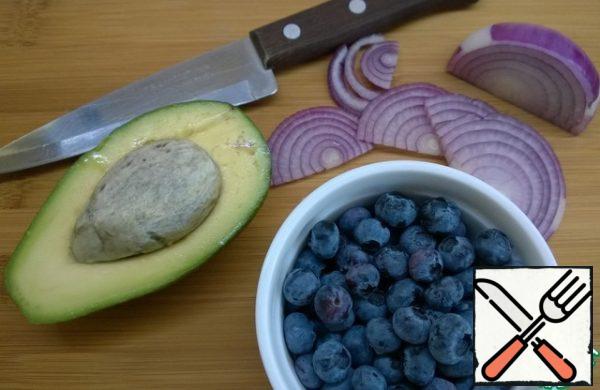 Cut the red onion into half rings. Cut the avocado into pieces and mix with the lemon juice. Wash and dry blueberries or blueberries. Cut the feta cheese into squares.