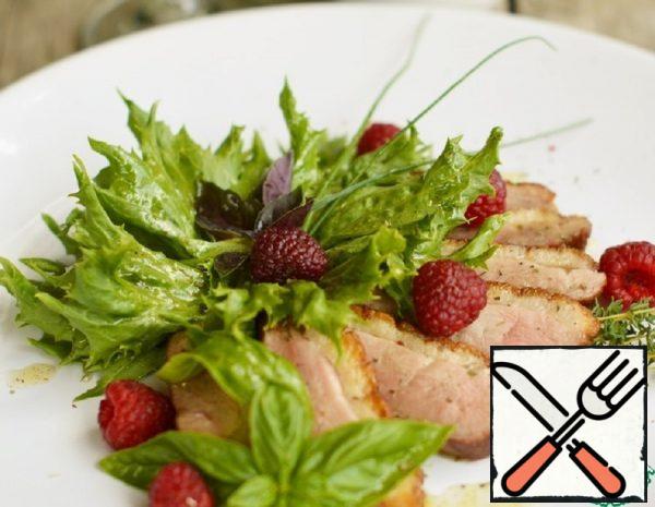 Cut the duck breast into slices. Put the pieces of duck, lettuce and raspberries on a plate. Garnish with a sprig of Basil, thyme and green onions. Pour the dressing on top of the salad.