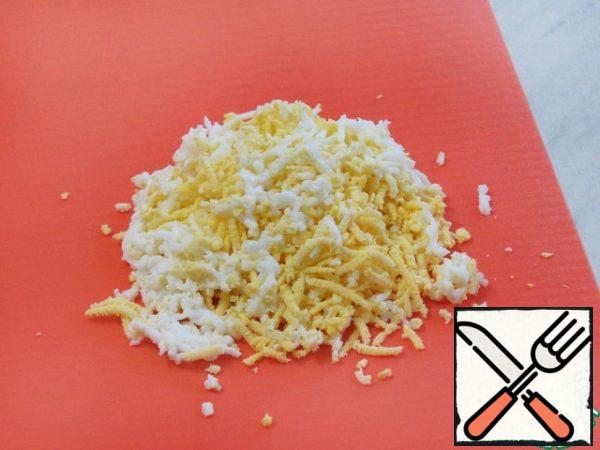 Boil the eggs, cool them and grate them on a fine grater.