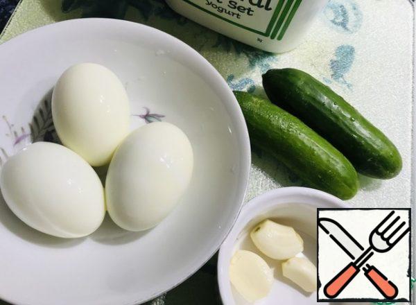 Boil the eggs-clean, fresh cucumbers partially peel, 3 cloves of garlic.