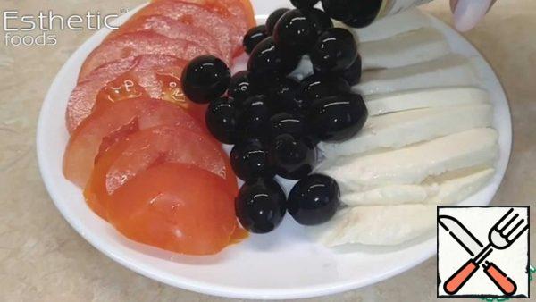Cut the tomato, cheese and drain the liquid from the olives.