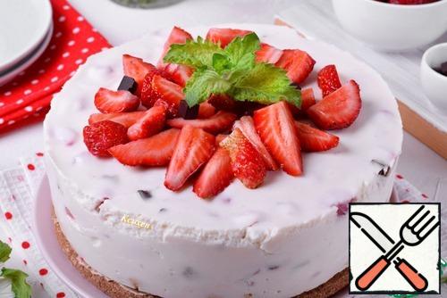 The finished cake is carefully removed from the mold, first removing the rim, and then removing the acetate tape. Transfer the cheesecake to a serving dish and garnish with strawberries, chocolate and mint.