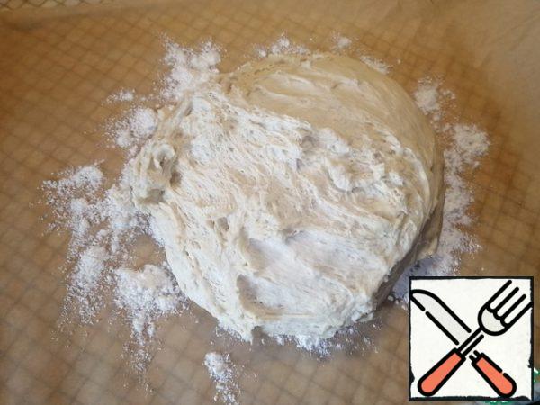 Cut off a large piece of parchment paper to cover the entire baking sheet. Sprinkle the surface with flour and knead our dough for 10 minutes.
