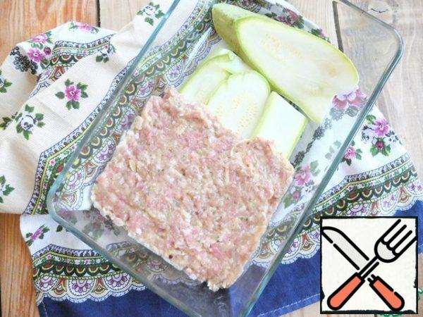 In a baking container, spread thinly sliced strips of zucchini.
On top of meat layer.