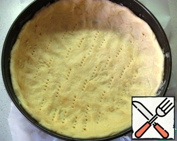 Put 2/3 of the dough in a baking dish (22 cm diameter, covered the bottom with parchment, and smeared the side with butter). Distribute on the bottom, form the sides, prick with a fork over the entire surface.

Remove the form with the cake preparation and 1/3 of the dough (pre-wrap with film) in the refrigerator while we are engaged in filling.