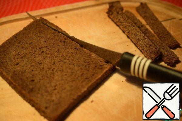Cut off the crusts from slices of black bread.