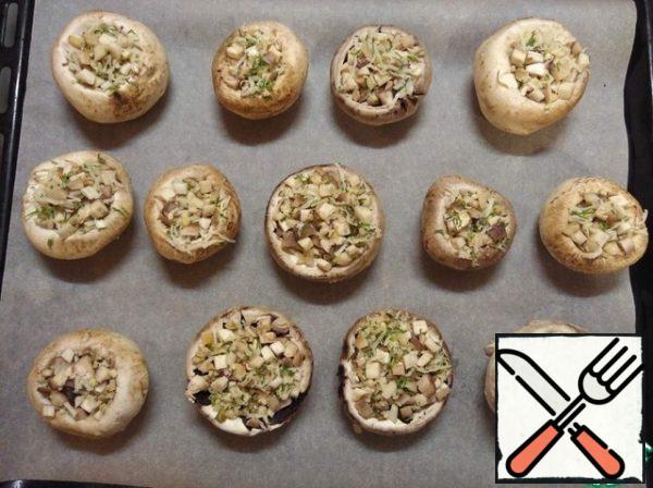 Put the mushrooms on a baking sheet. Top with a little grated cheese on a small grater.
