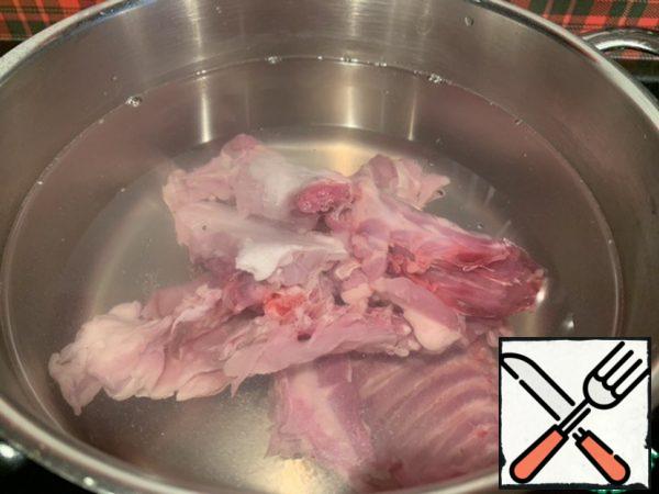 Fillet and the rest of the rabbit (neck, ribs and back of the spine), put in a pan, pour 2 liters of cold water.