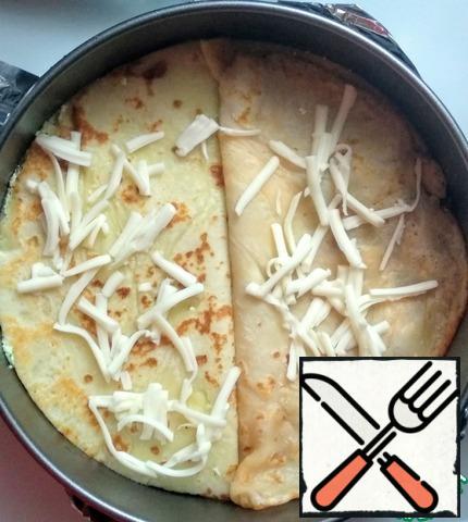 Split baking dish cover with baking paper and grease with vegetable oil (1 tbsp.). Arrange the pancakes in the order of alternating fillings. Each layer is slightly sprinkled with grated cheese, so that the pancakes "grabbed".